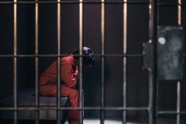 a-woman-in-an-orange-jumpsuit-sits-in-a-prison-cell Ολόσωμη Φόρμα Πορτοκαλί