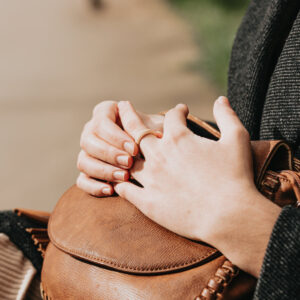 hands-lay-on-a-brown-leather-bag-on-a-persons-lap Τσάντα Καφέ