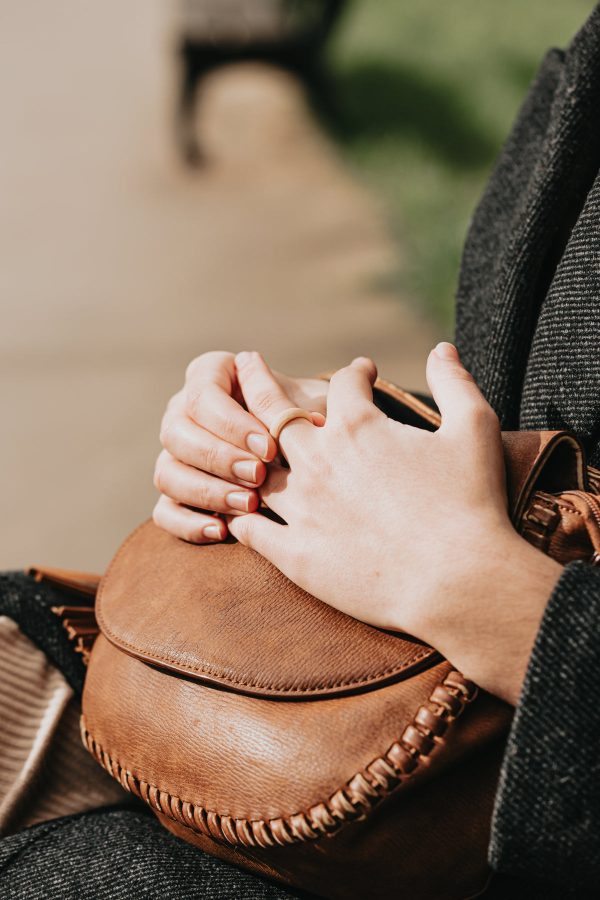 hands-lay-on-a-brown-leather-bag-on-a-persons-lap Τσάντα Καφέ