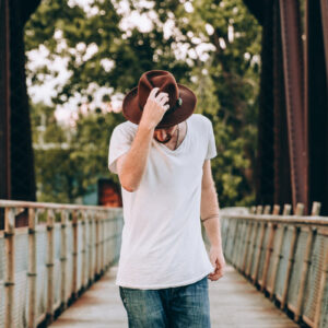 mens-fashion-walking-across-bridge-holding-hat Καπέλο Ανδρικό