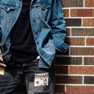 person-in-a-blue-jean-jacket-leans-against-a-red-brick-wall Μπουφάν Vintage