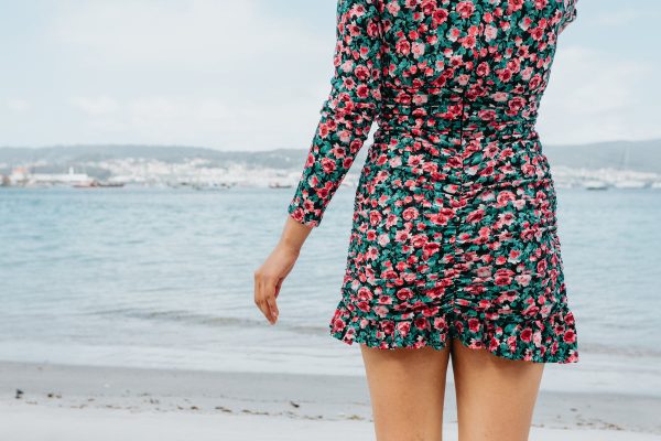 person-in-a-floral-dress-stands-on-a-beach-facing-the-water Φόρεμα Φλοράλ 009