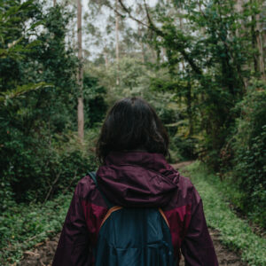 Woman back in trekking clothes in the middle of a super green rainy forest during autumn Αδιάβροχο Κόκκινο
