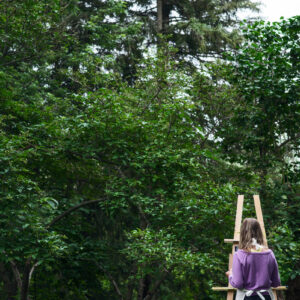 person-in-purple-sweater-paints-at-an-easel-outdoors Πουλόβερ Μωβ