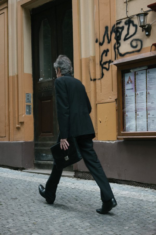 person-walks-quickly-with-bags-by-a-brown-building Τσάντες Καφέ