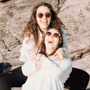 two-people-in-sunglasses-sit-in-front-of-a-large-brown-rock Γυαλιά Ηλίου Καφέ