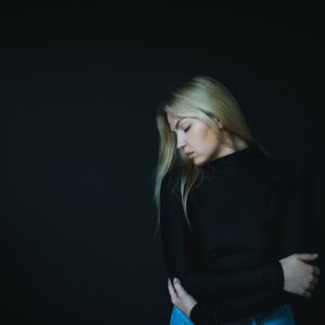 woman-in-black-sweater-hugs-herself-against-black Πουλόβερ Μαύρο