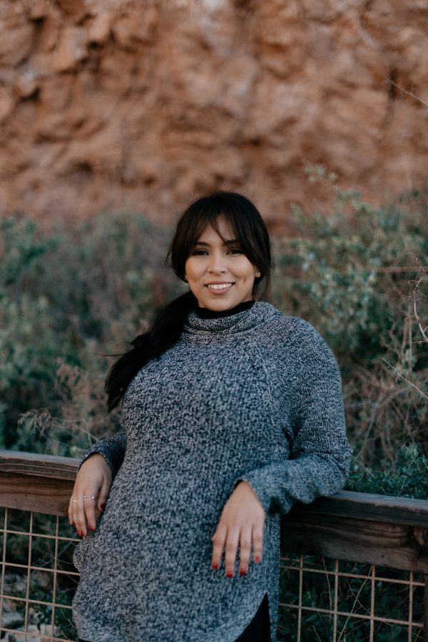 woman-in-grey-sweater-smiles-and-leans-against-a-railing Πουλόβερ Γκρι