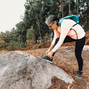 Old woman tying her tennis laces in the forest on sport clothes and shoes Παπούτσια