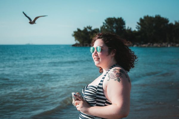 young-woman-in-sunglasses-holding-camera-facing-beach Γυαλιά Ηλίου 025
